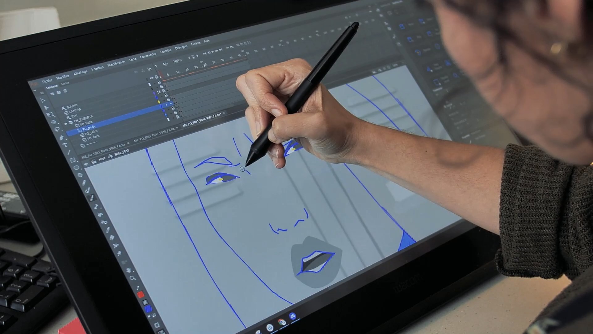 Une animatrice travaille sur une tablette graphique pour tracer les contours d'un personnage